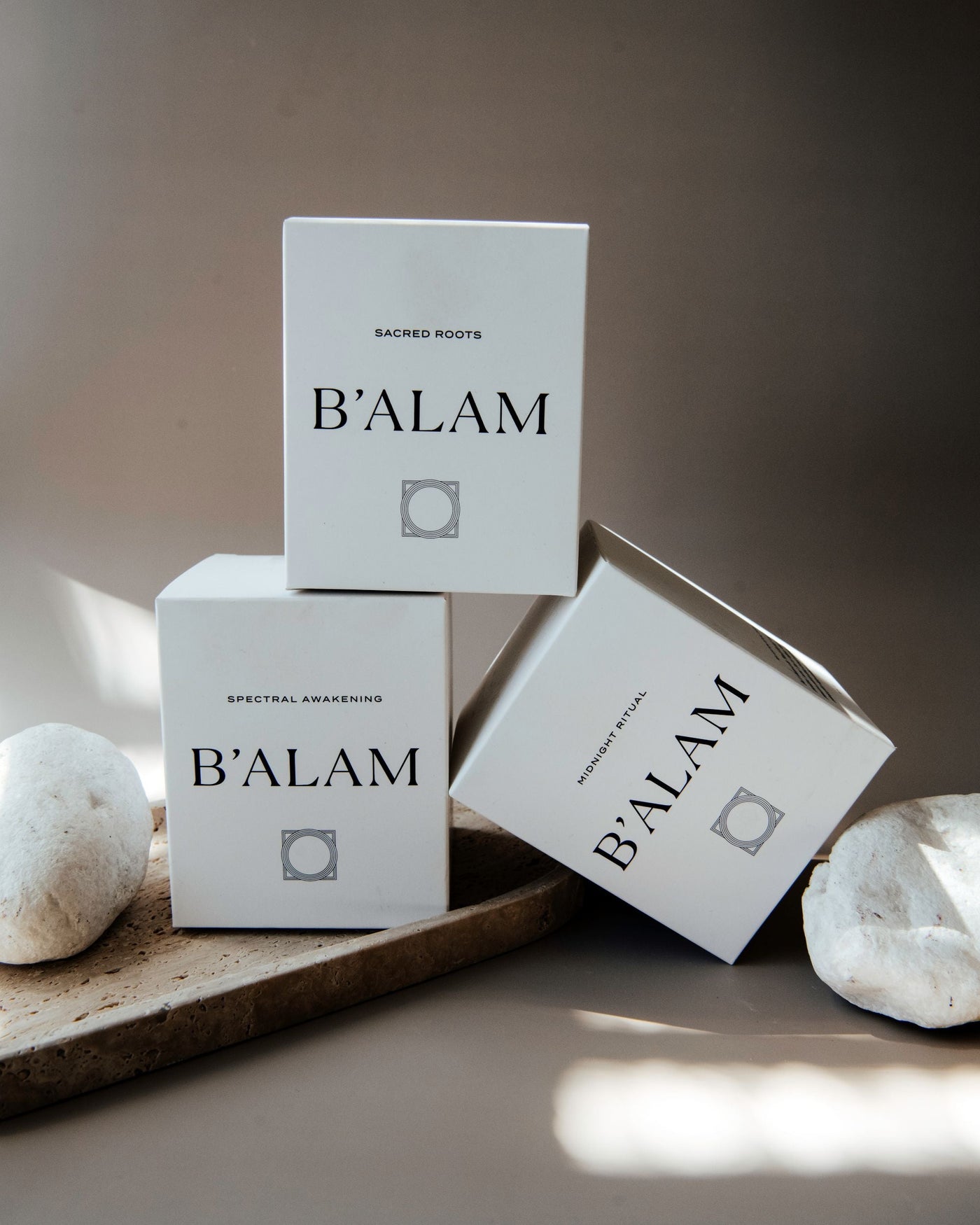 B'ALAM luxury candle packaging on a stone surface with a neutral background