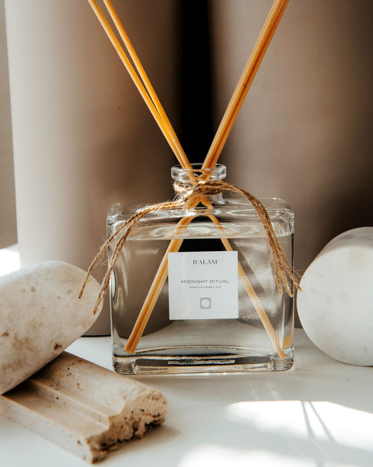 Clear glass diffuser bottle with wooden sticks on a neutral background